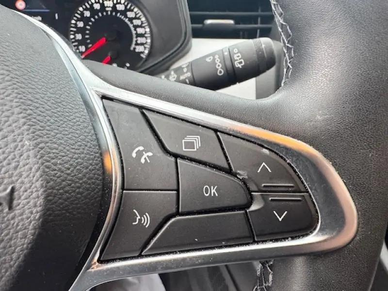 Gros plan sur les commandes multifonctions au volant côté droit de la Renault Clio blanc glacier 2023.