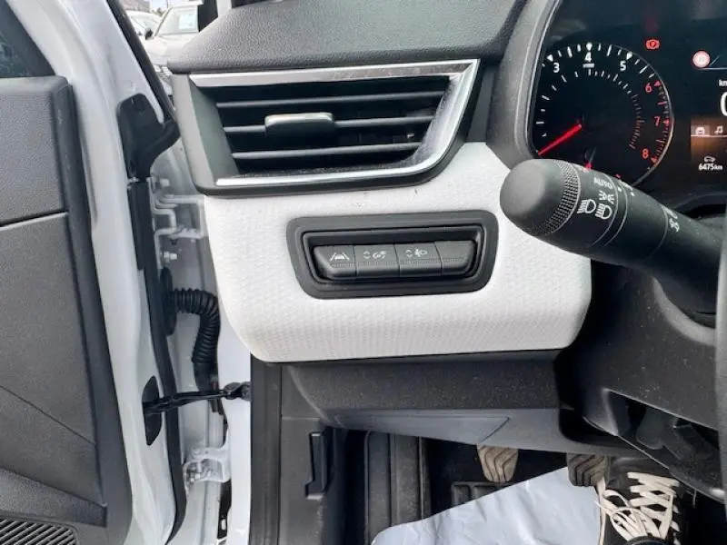 Détail du tableau de bord côté gauche d'une Renault Clio blanc glacier 2023 avec commandes d'assistance et aérateur.