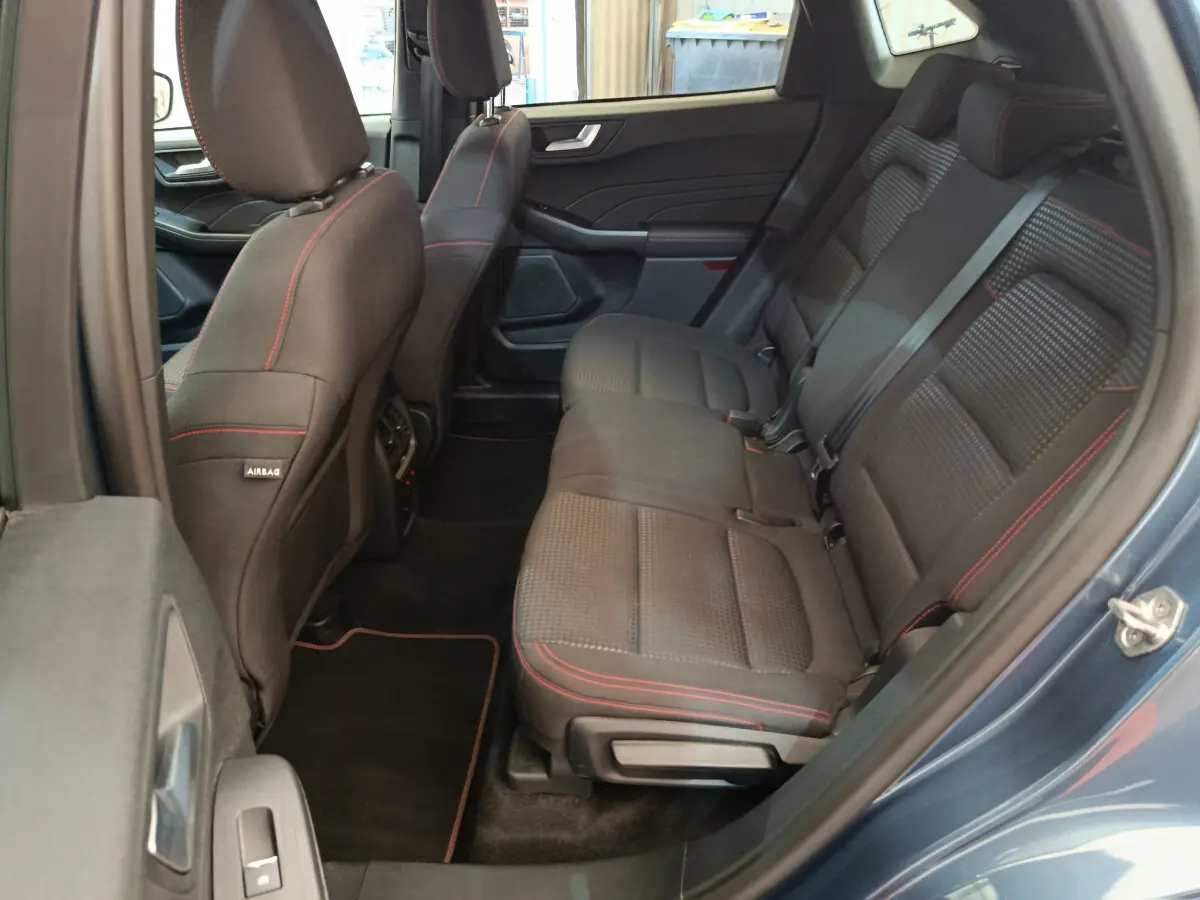 Vue côté droit des sièges arrière noirs avec surpiqûres rouges du Ford Kuga 2024 bleu, intérieur spacieux et moderne.