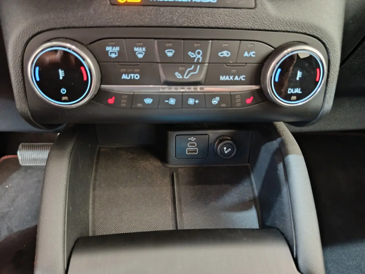 Vue rapprochée de la console centrale du Ford Kuga 2024, montrant les commandes de climatisation et ports USB.