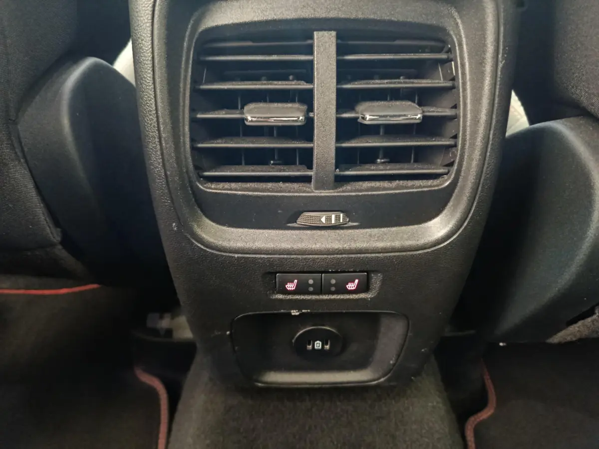 Vue rapprochée de la console arrière noire du Ford Kuga bleu 2024, avec aérateurs, commandes de sièges chauffants et prise 12V.