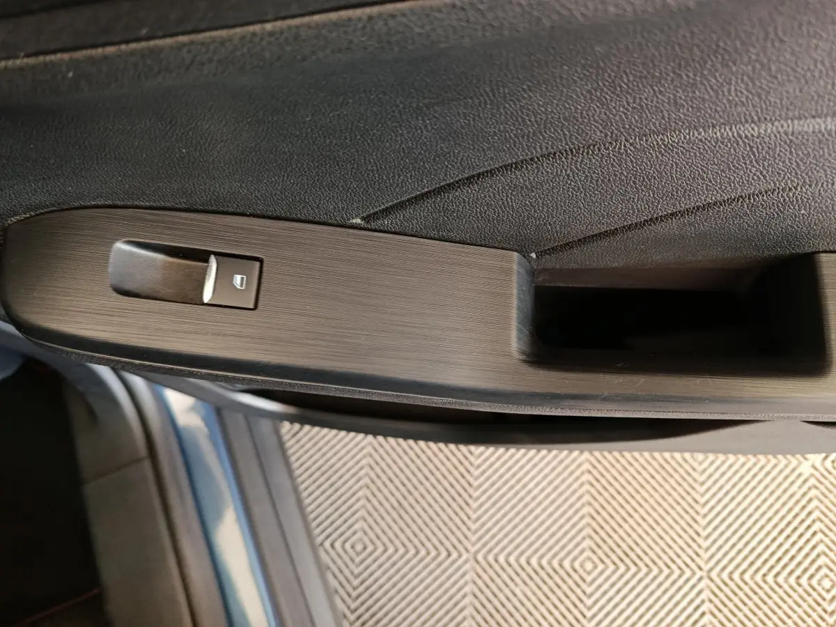 Gros plan sur la poignée intérieure côté gauche de la porte d’un Ford Kuga bleu 2024 avec bouton de verrouillage.