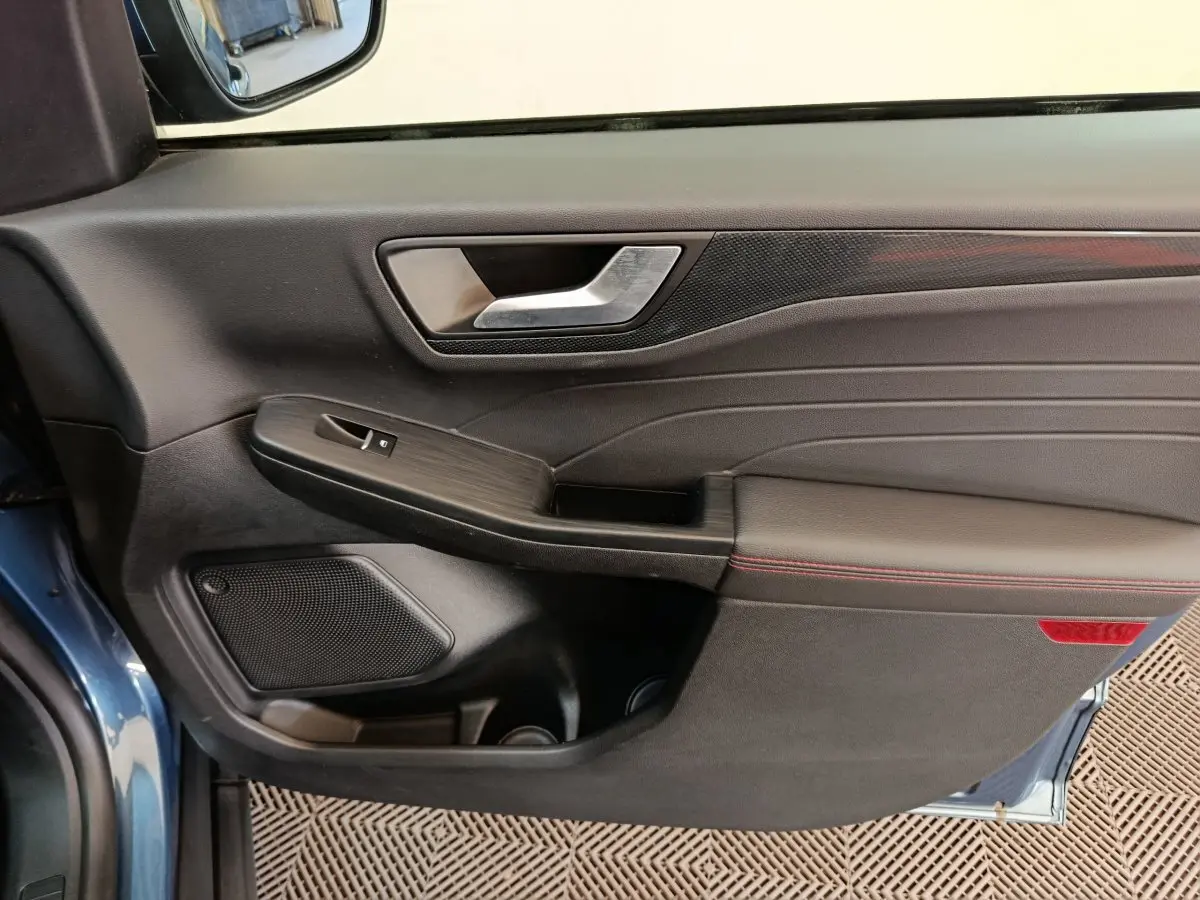 Vue intérieure du panneau de porte avant gauche bleu du Ford Kuga 2024, finition St Line avec surpiqûres rouges.