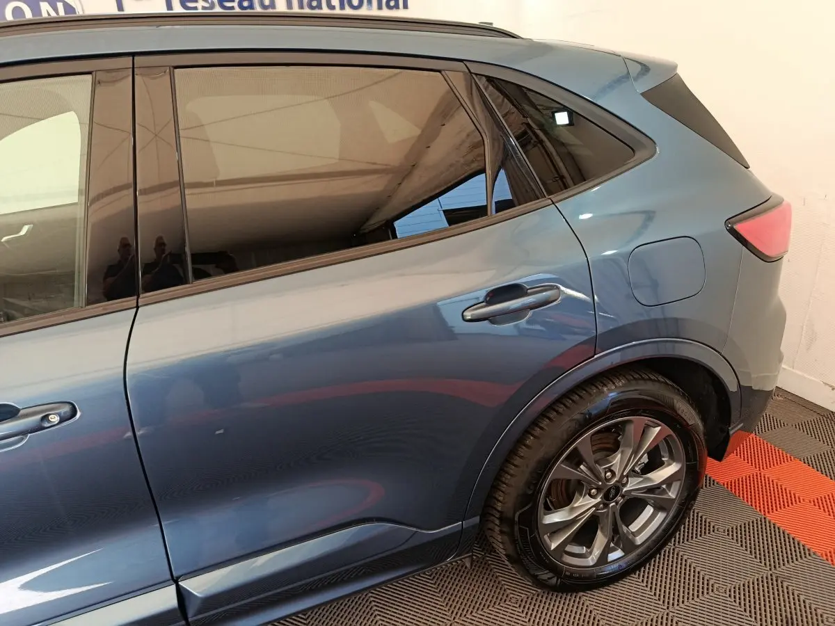 Vue latérale arrière droite du Ford Kuga 2024 bleu métallisé, mettant en valeur la roue alliage et les vitres teintées.