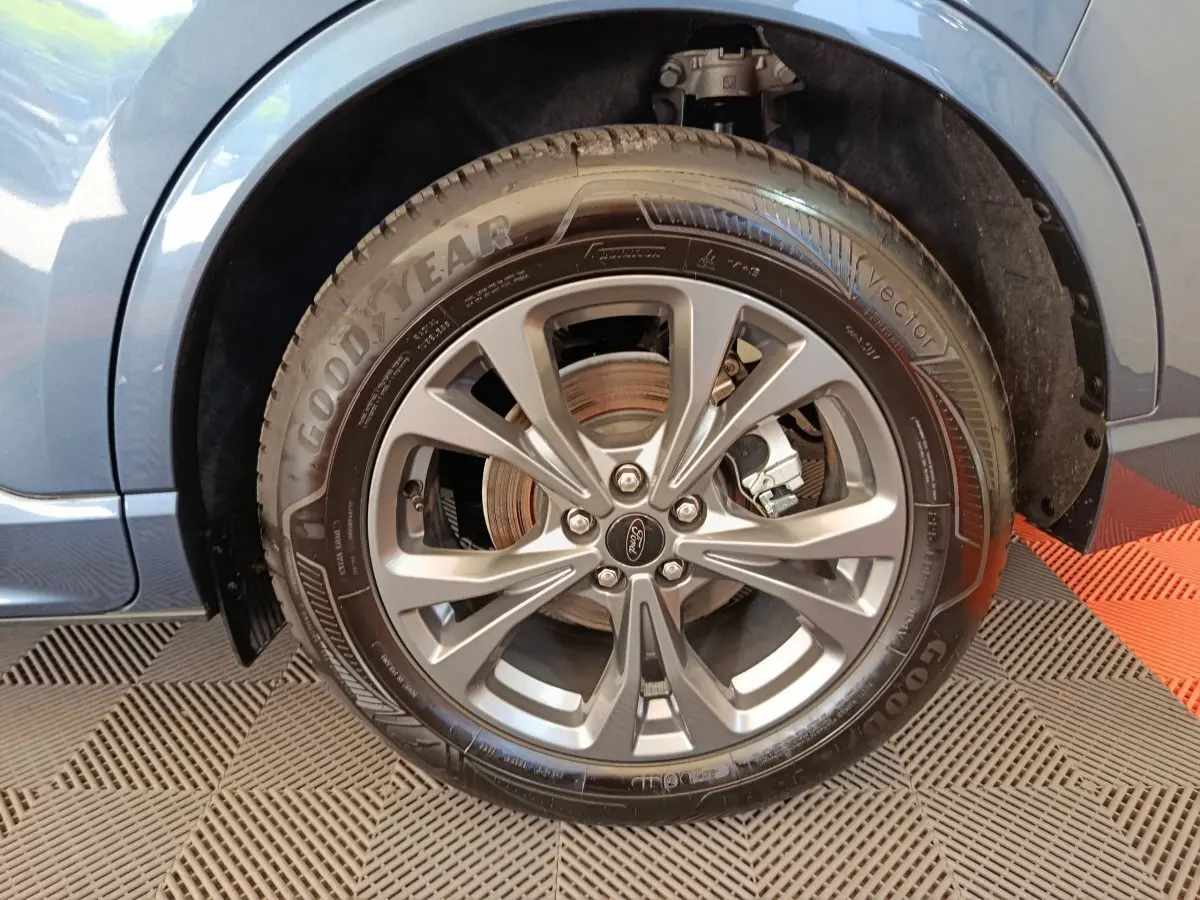 Gros plan sur la roue avant droite bleu métallisé du Ford Kuga 2024 avec jante alliage et pneu Goodyear.