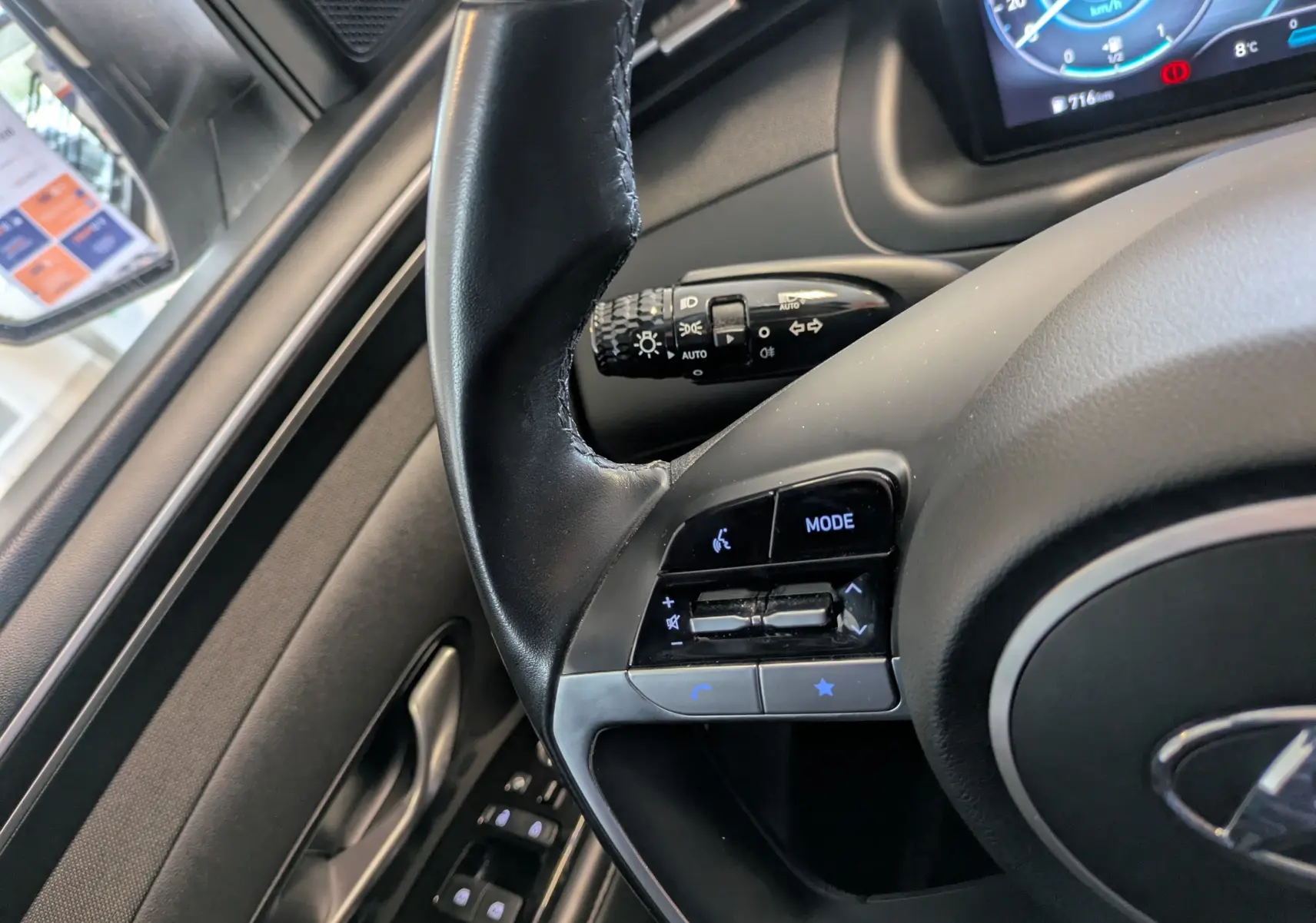 Gros plan sur le volant côté gauche d’un Hyundai Tucson blanc 2021, avec commandes audio et tableau de bord numérique.