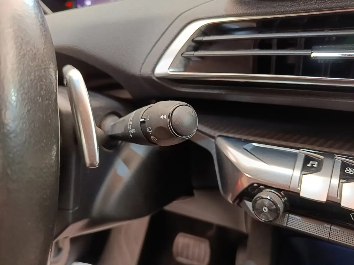 Détail intérieur du Peugeot 3008 2022 montrant la commande de clignotant et partie du tableau de bord noir.