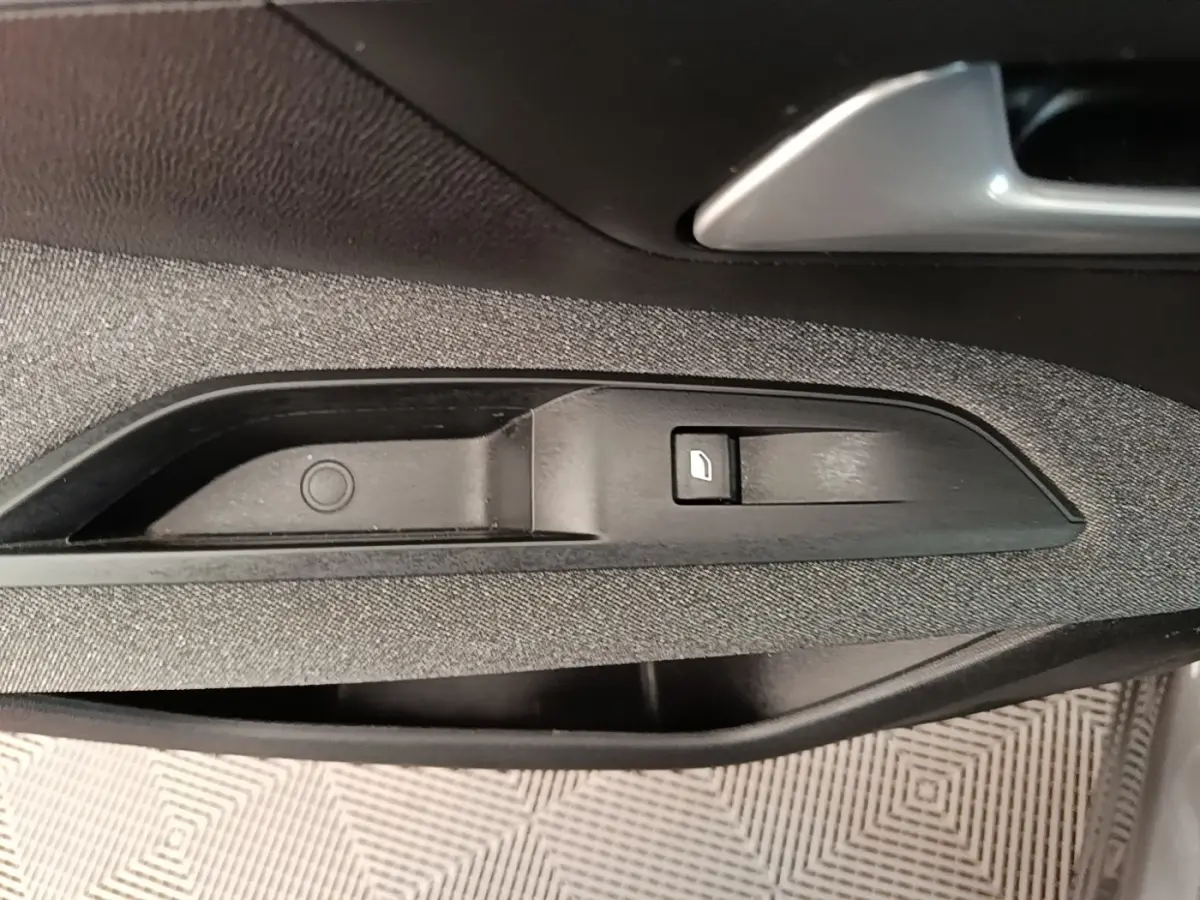 Détail de la commande de verrouillage de porte sur la garniture intérieure côté conducteur d’un Peugeot 3008 gris foncé.