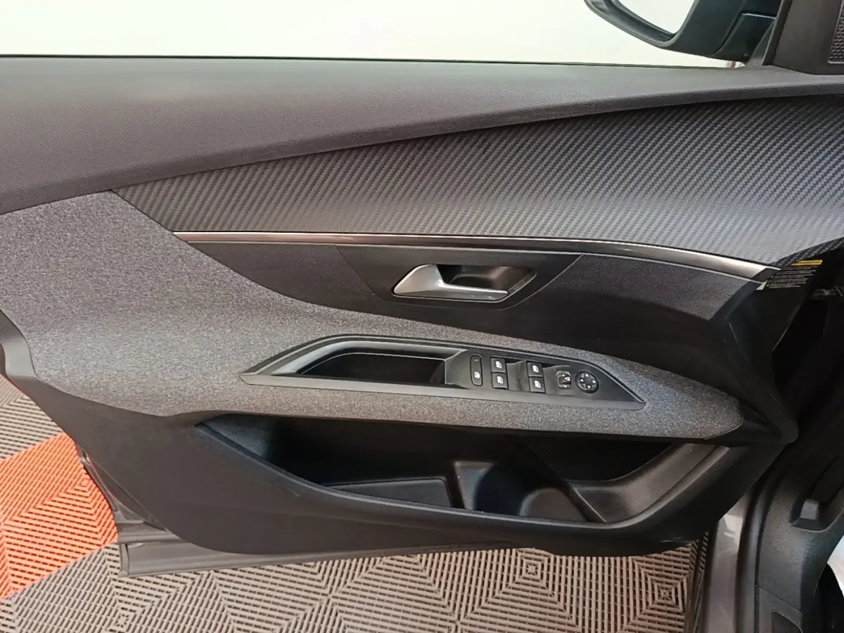 Vue rapprochée de la porte avant gauche du Peugeot 3008 2022, avec commandes électriques et finition tissu gris foncé.