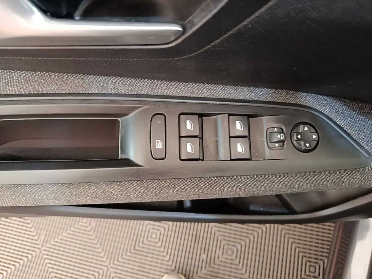 Gros plan sur la commande des vitres électriques côté conducteur d’un Peugeot 3008 gris foncé, avec tissu noir et boutons noirs.
