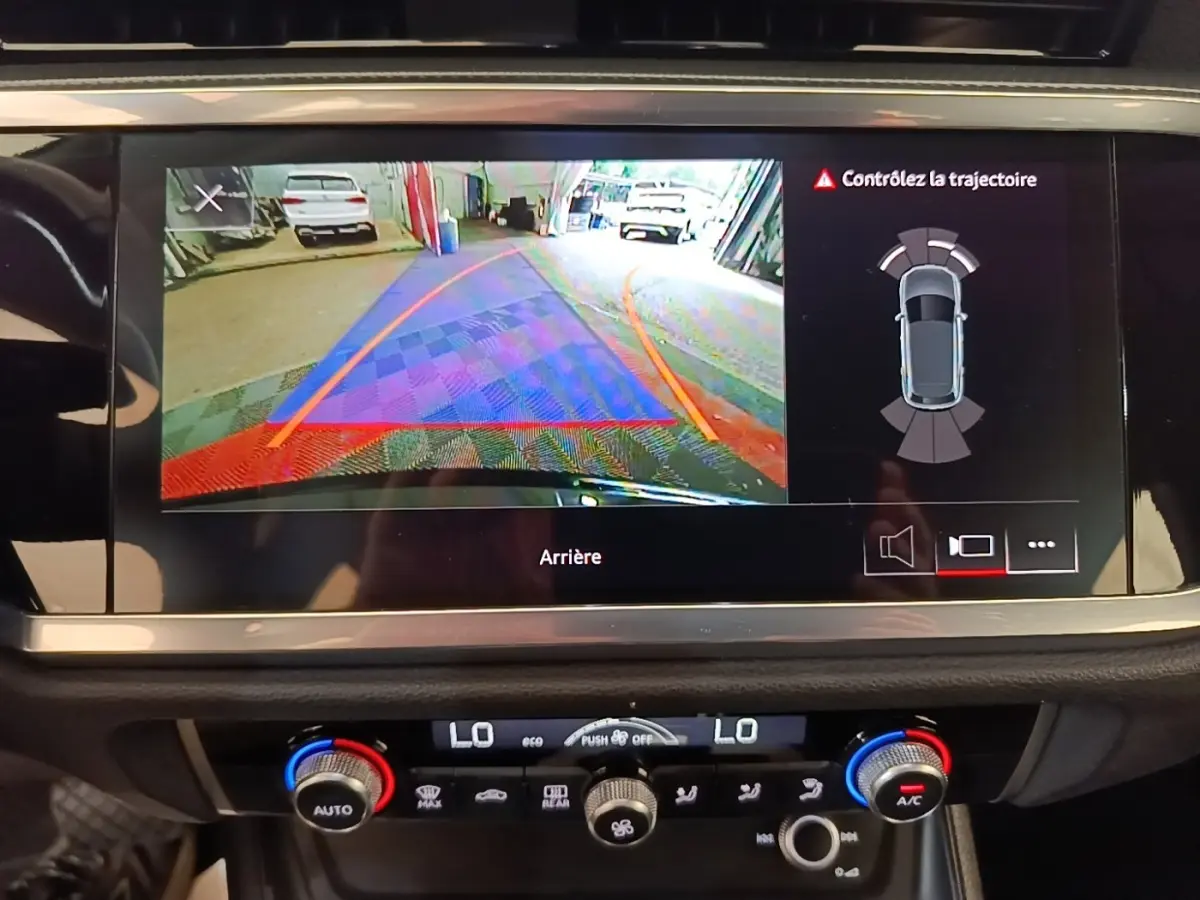 Écran tactile intérieur montrant la caméra de recul et l’aide au stationnement d’un Audi Q3 hybride rechargeable 2023.