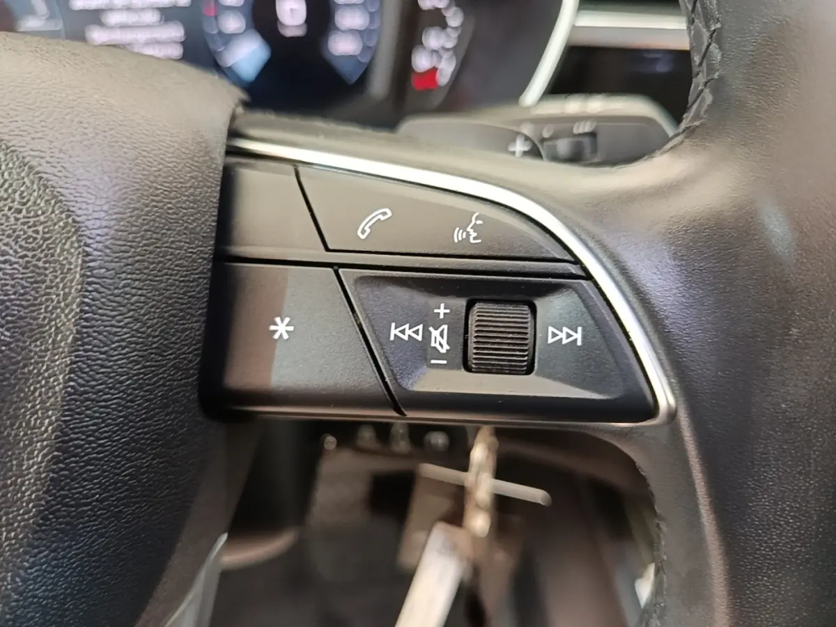 Gros plan sur le côté droit du volant cuir noir d’Audi Q3 45 TFSI e avec commandes audio et vocales.