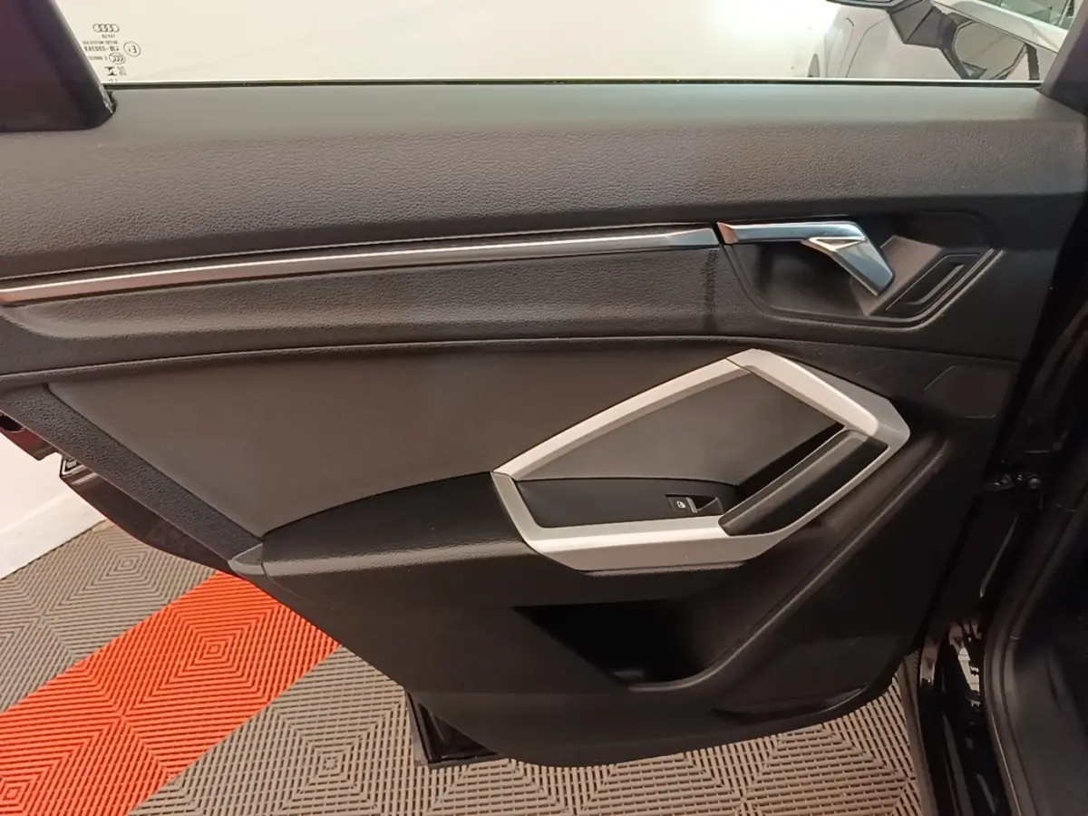 Vue intérieure de la porte côté gauche d’un Audi Q3 45 TFSI e 2023, avec garniture noire et insert argenté.