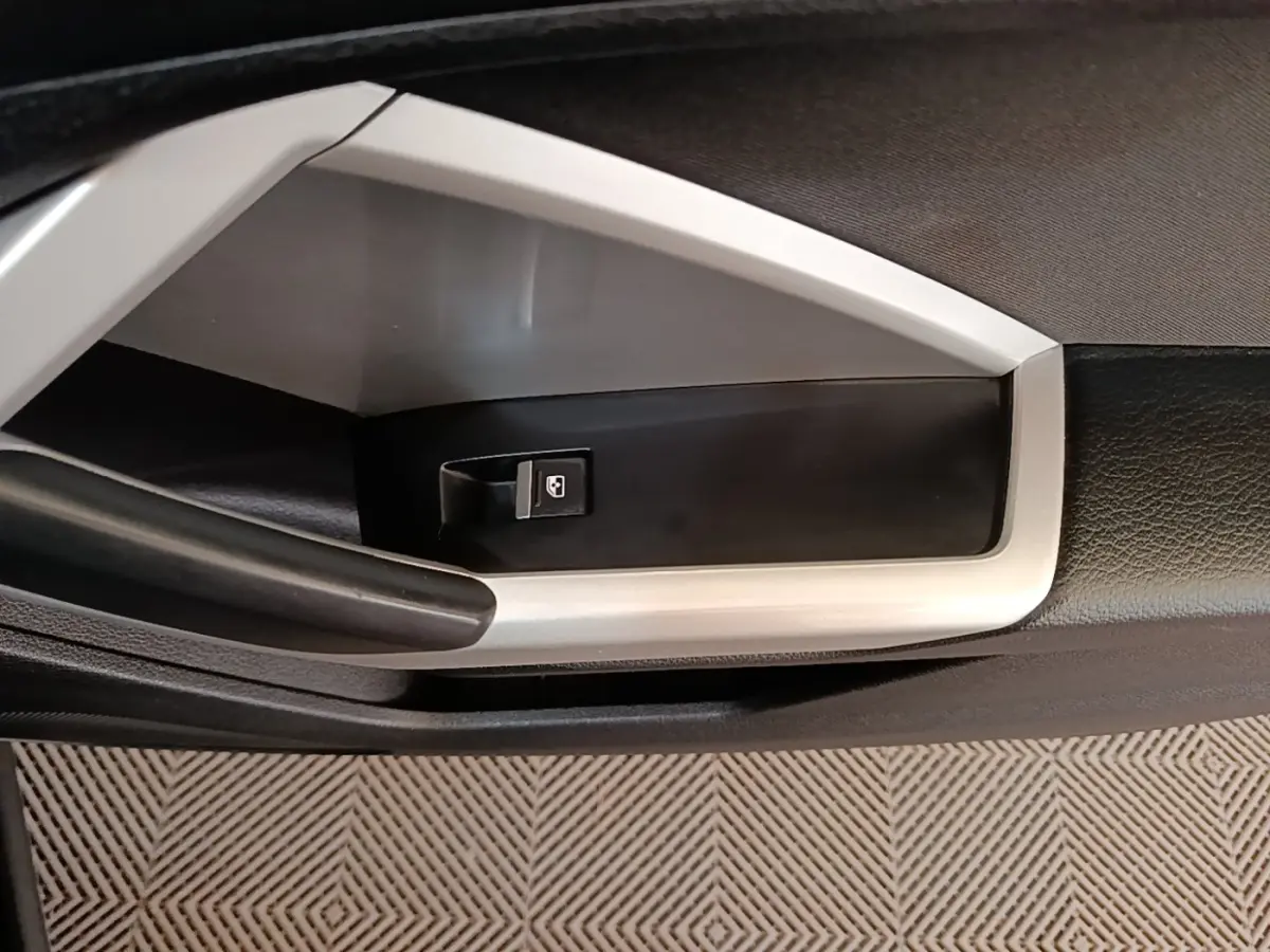 Gros plan sur la commande de lève-vitre côté gauche de la porte intérieure noire et grise de l'Audi Q3 2023.