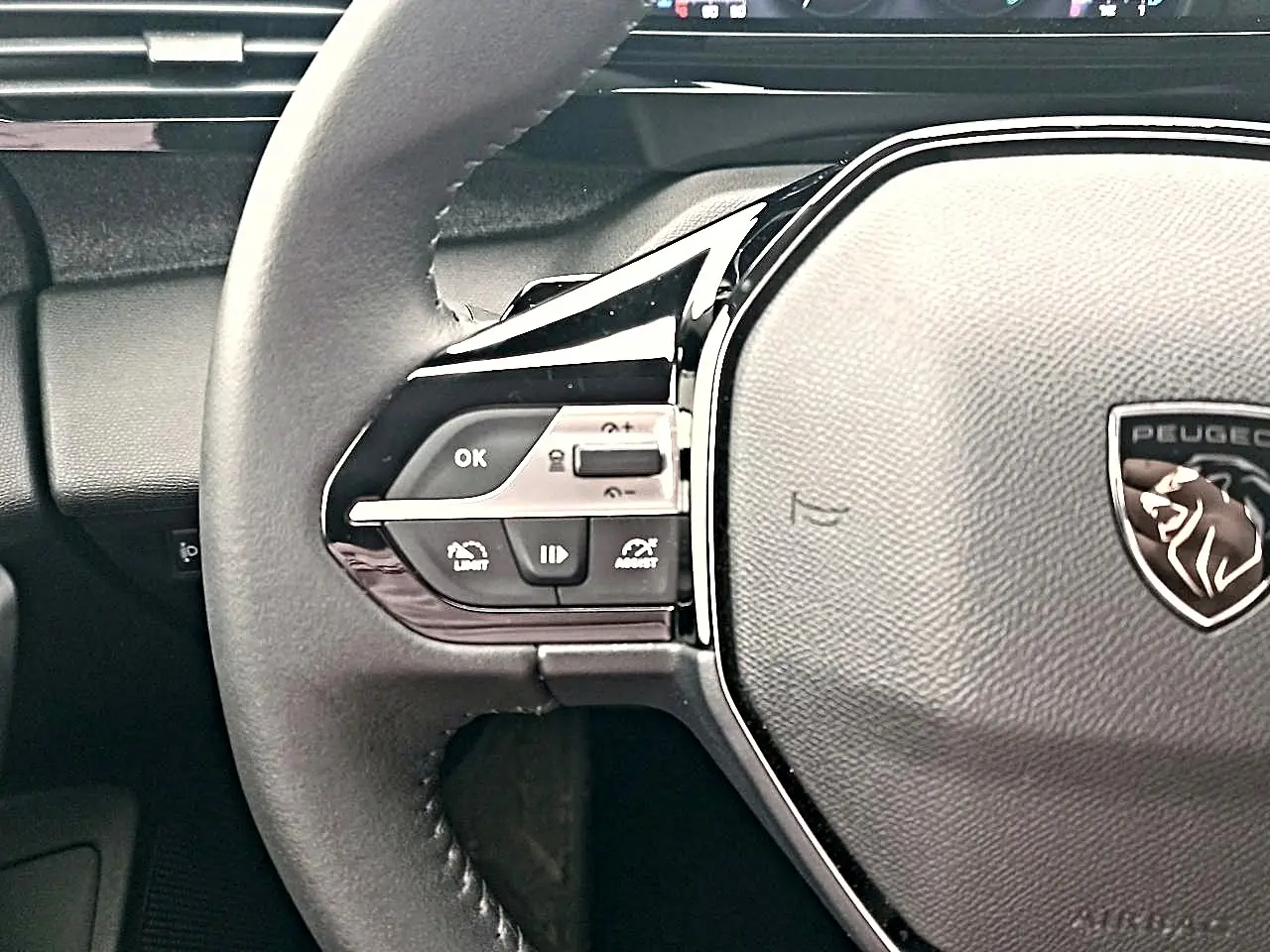Gros plan sur le volant cuir multifonction gris du Peugeot 408 Hybrid 145 allure avec commandes intégrées côté gauche.
