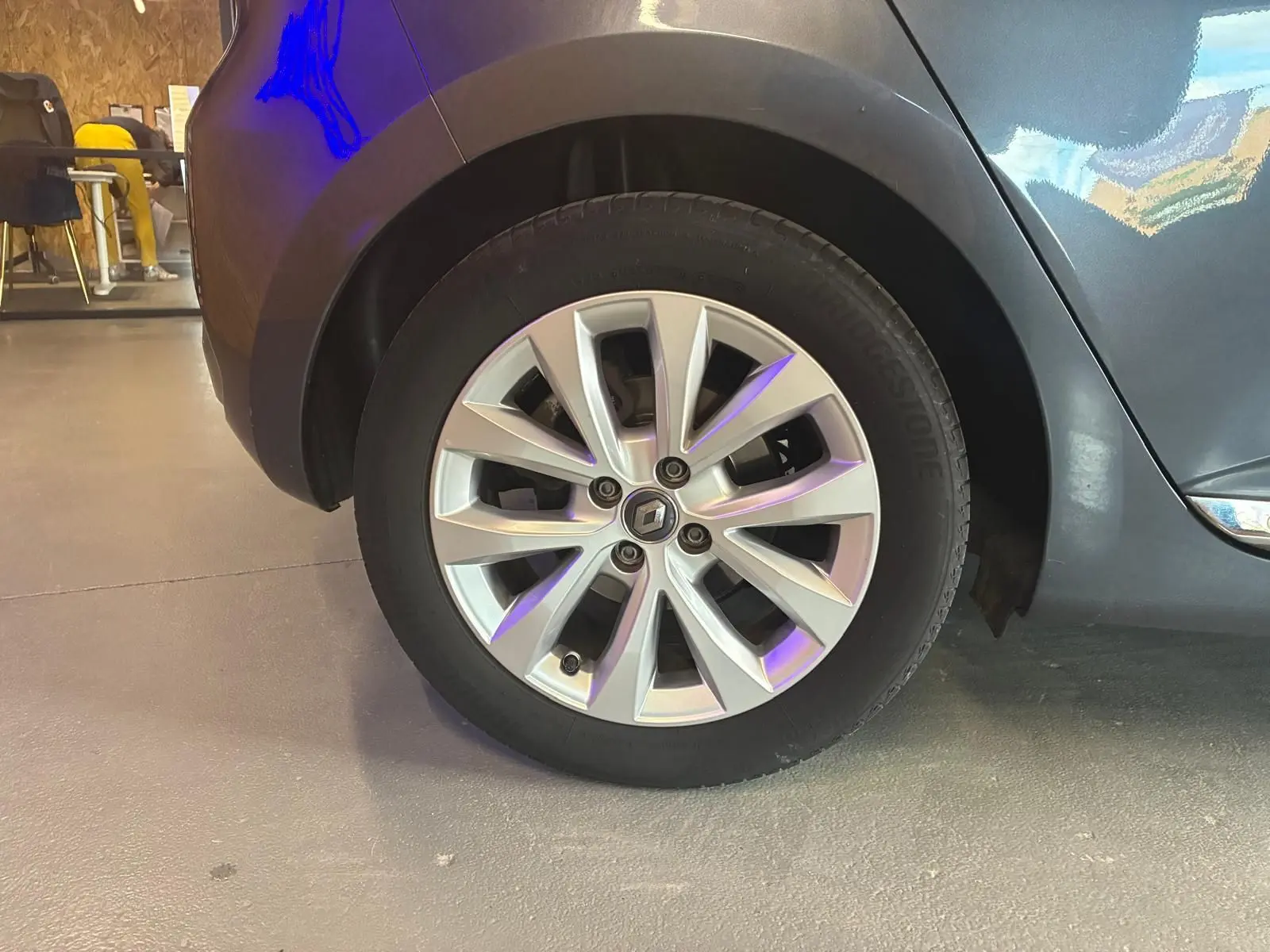 Gros plan sur la roue avant gauche d'une Renault Clio gris 2020 avec jante alliage et logo Renault visible.