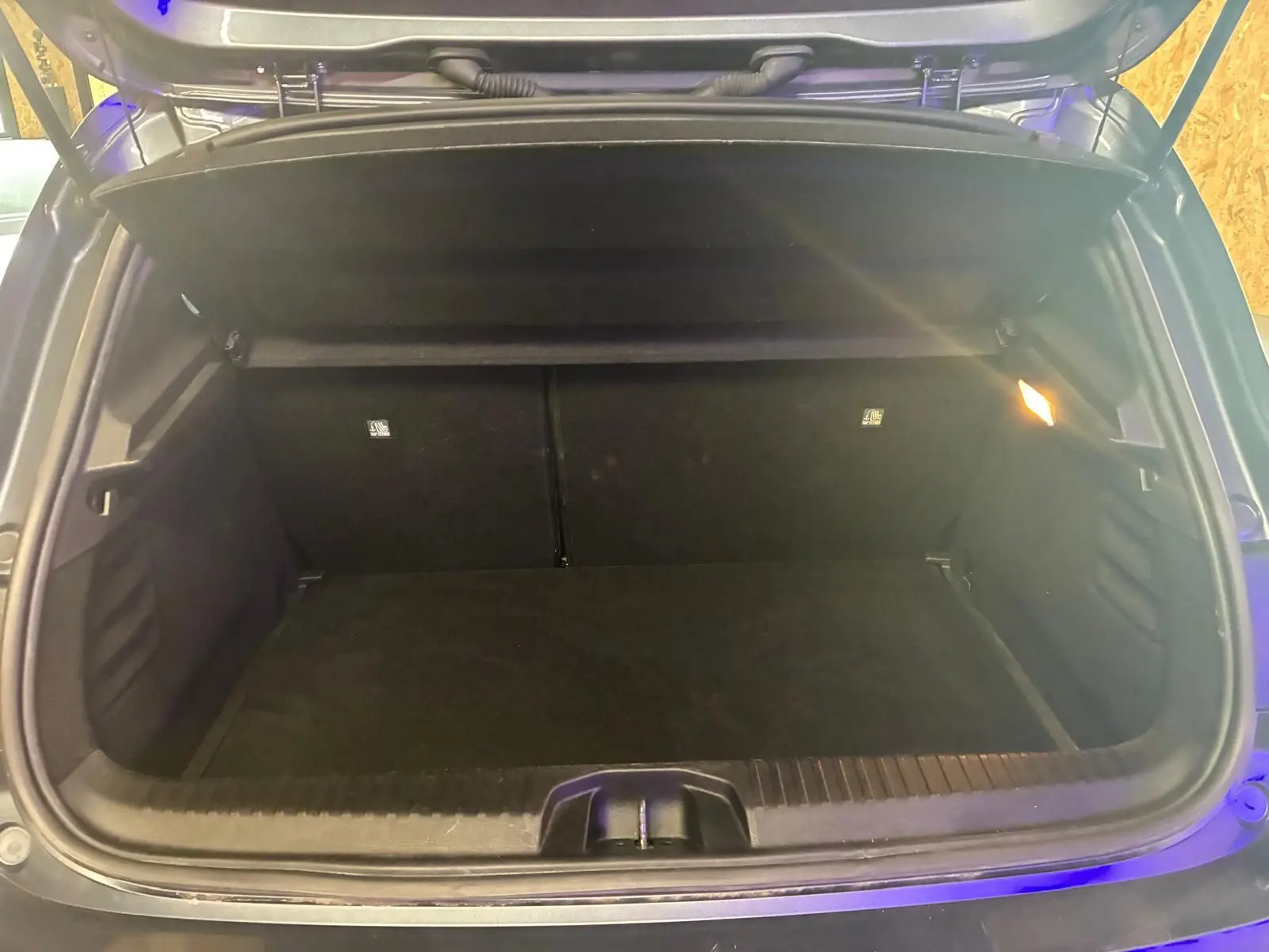 Coffre ouvert d'une Renault Clio gris 2020, vue arrière montrant un espace de chargement vide et éclairé.