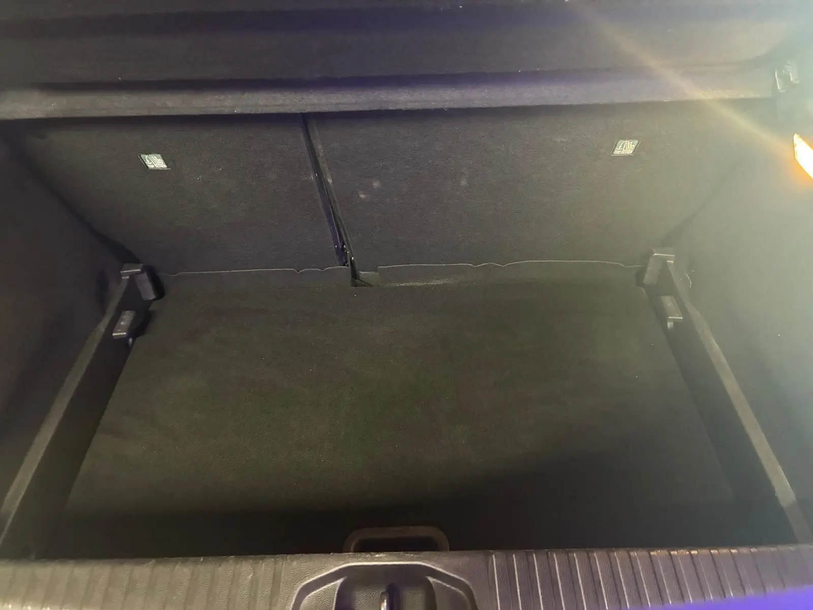 Coffre ouvert de la Renault Clio gris 2020, vue plongeante montrant l'espace de rangement vide et l'éclairage intérieur.