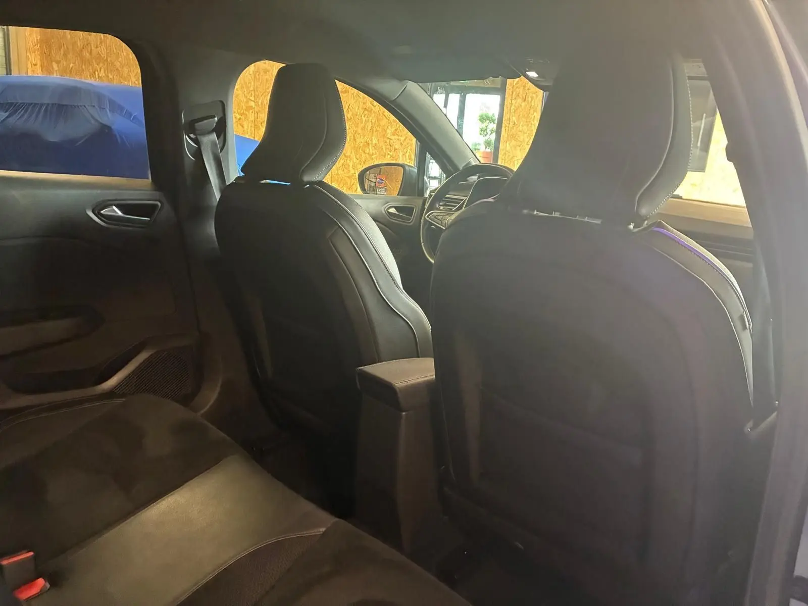 Vue intérieure arrière de la Renault Clio 2020 gris, montrant les sièges avant en tissu noir et la console centrale.