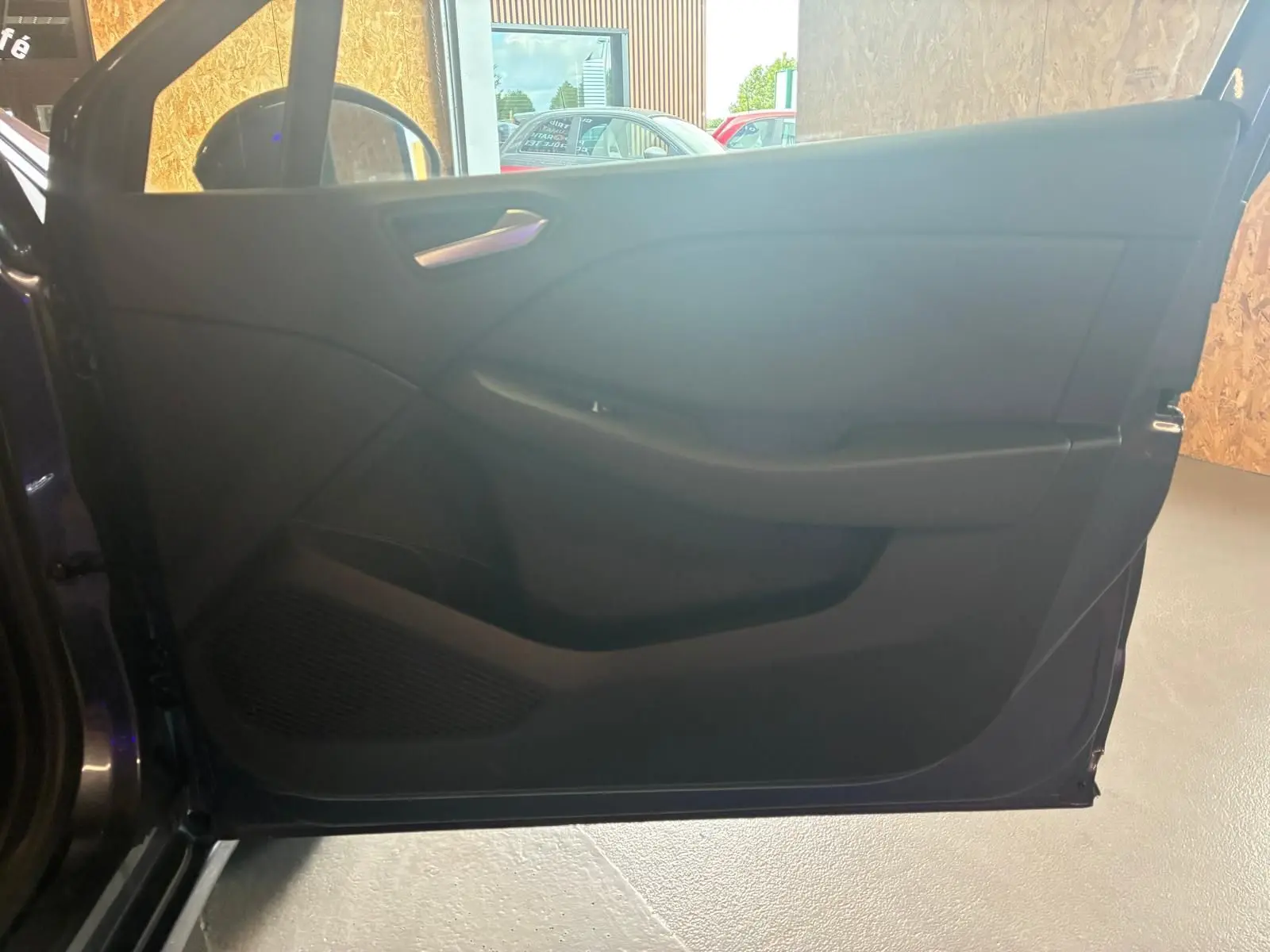 Intérieur de la porte côté gauche d'une Renault Clio gris 2020, avec poignée argentée et panneau noir épuré.