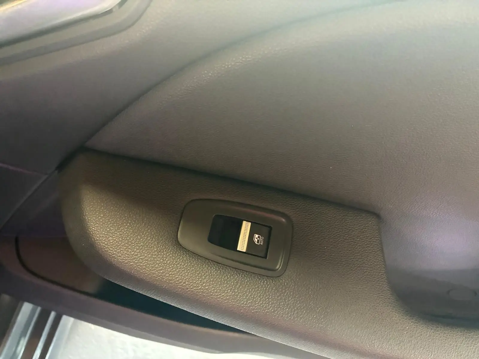 Bouton de commande de lève-vitre électrique sur la porte intérieure côté gauche d'une Renault Clio gris 2020.