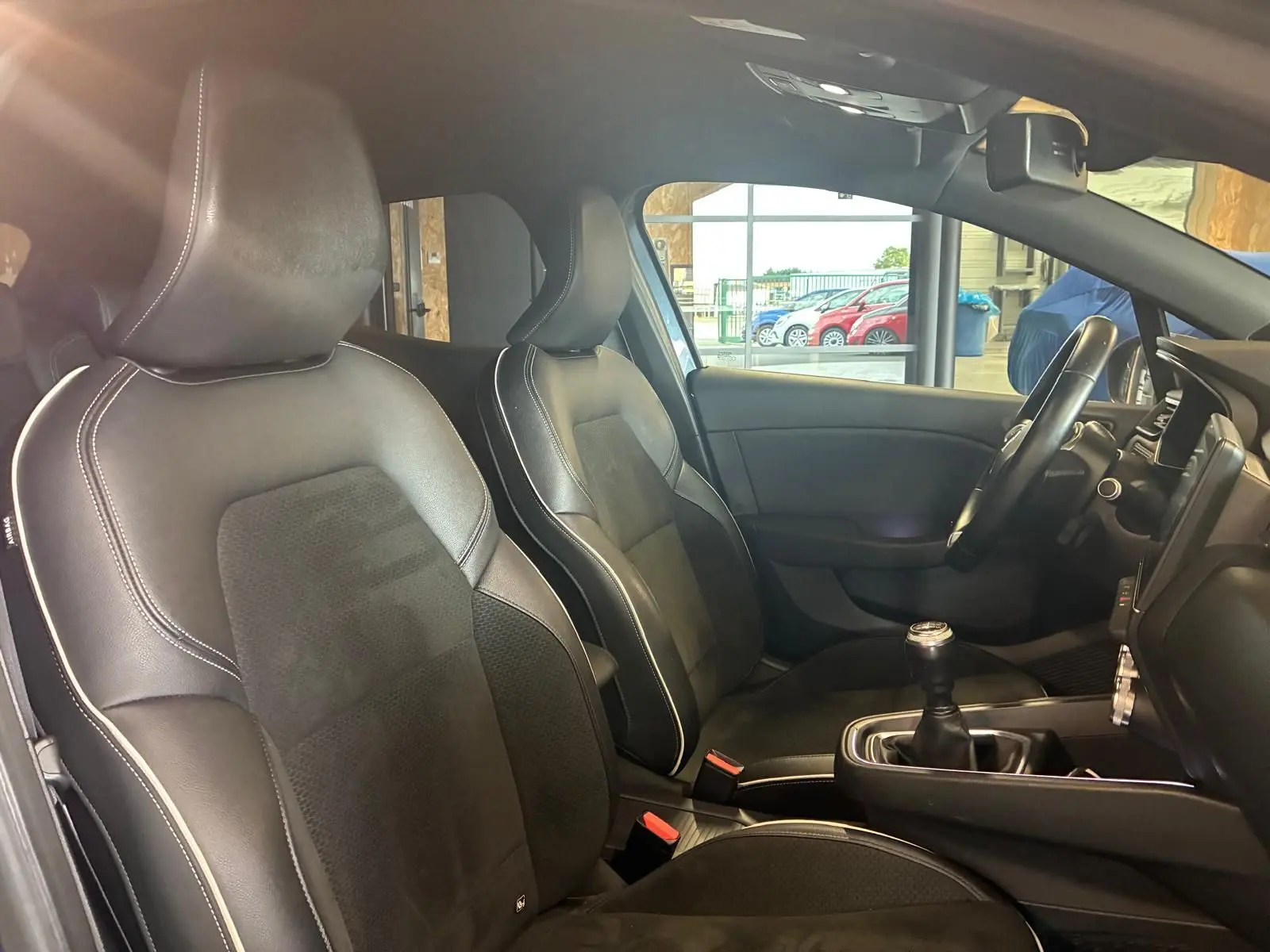 Intérieur de la Renault Clio 1.0 TCE 100 Intens 2020 montrant les sièges avant en tissu noir et volant multifonction.