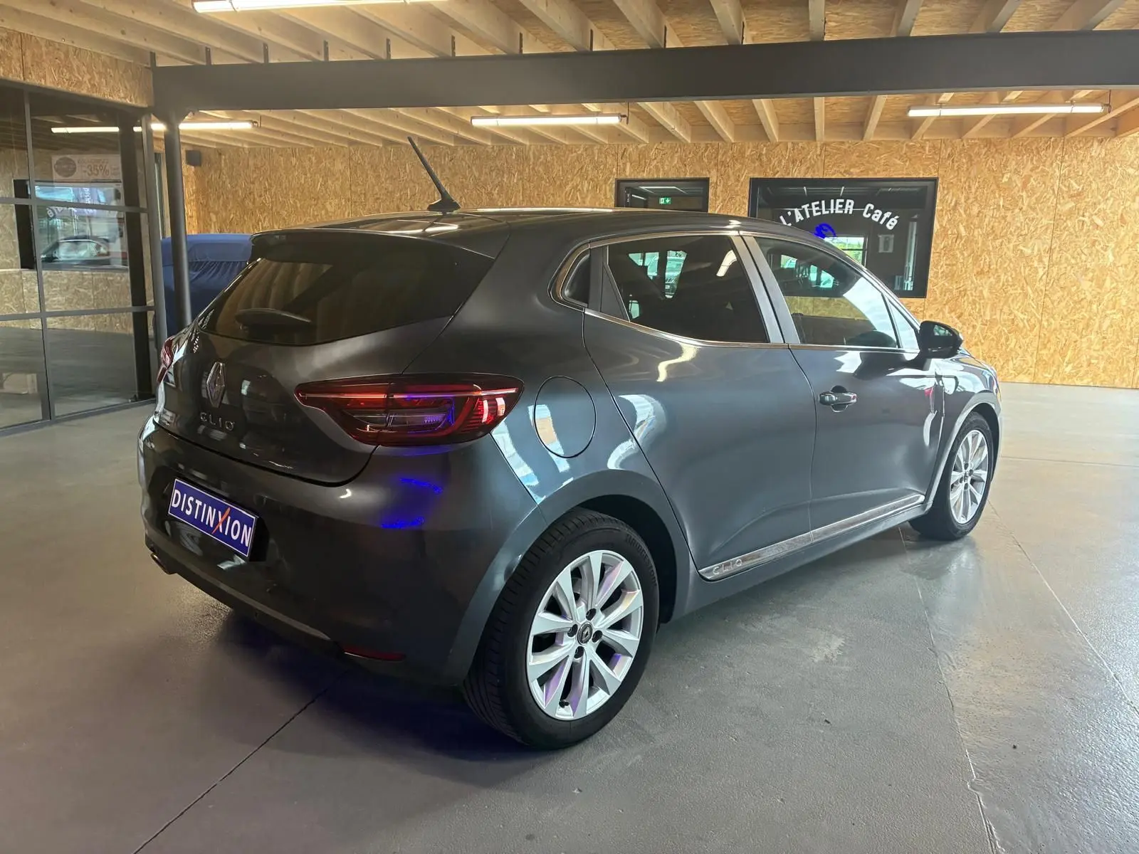 Vue 3/4 arrière droite d'une Renault Clio gris métallisé 2020, compacte et élégante, en intérieur showroom.