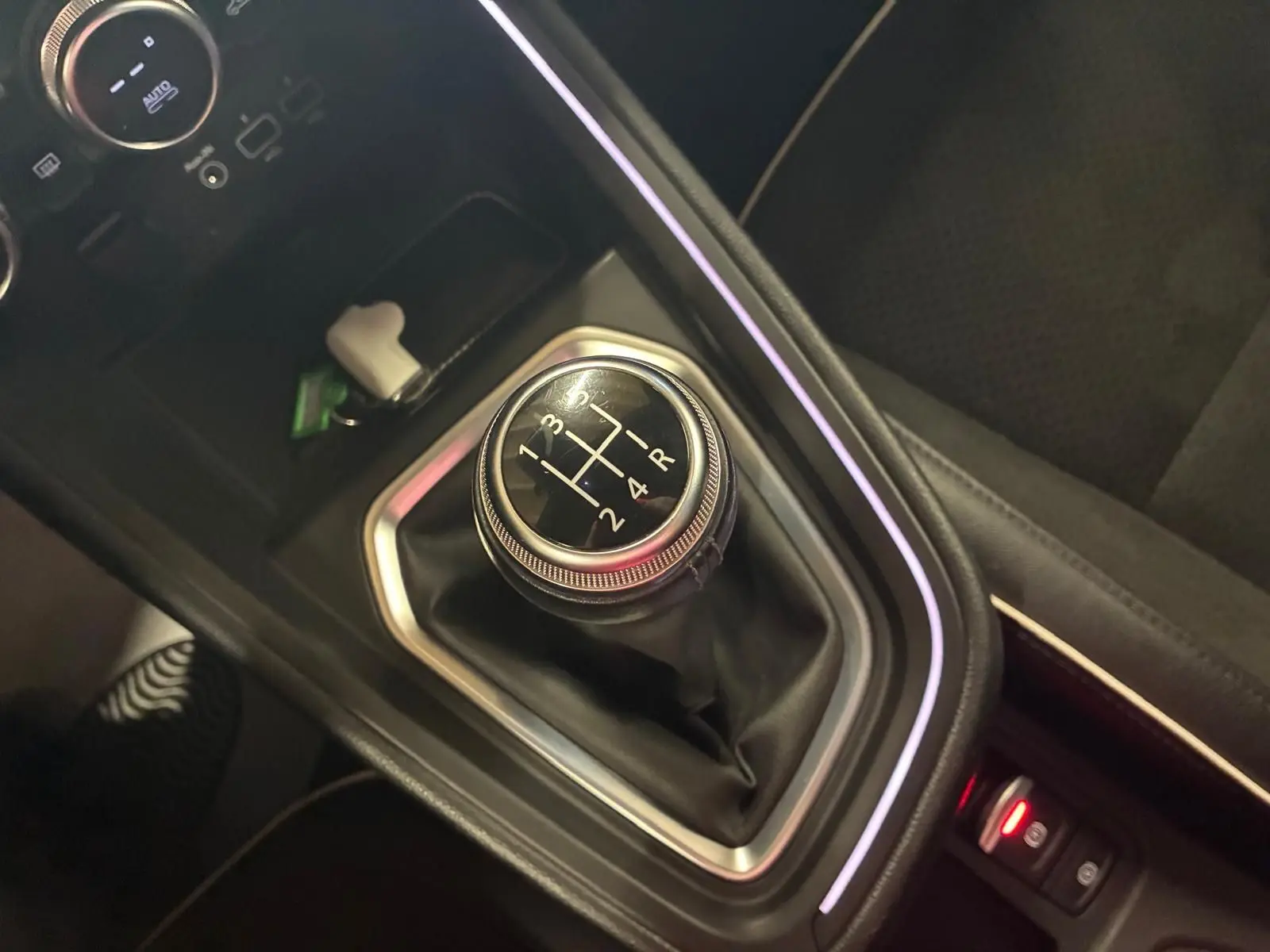 Le levier de vitesses manuel noir de la Renault Clio 1.0 TCE 100 Intens 2020, entouré d'un éclairage d'ambiance violet.