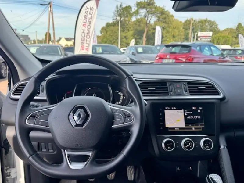 Vue intérieure du tableau de bord et volant cuir multifonction du Renault Kadjar blanc de 2020 avec écran tactile GPS allumé.