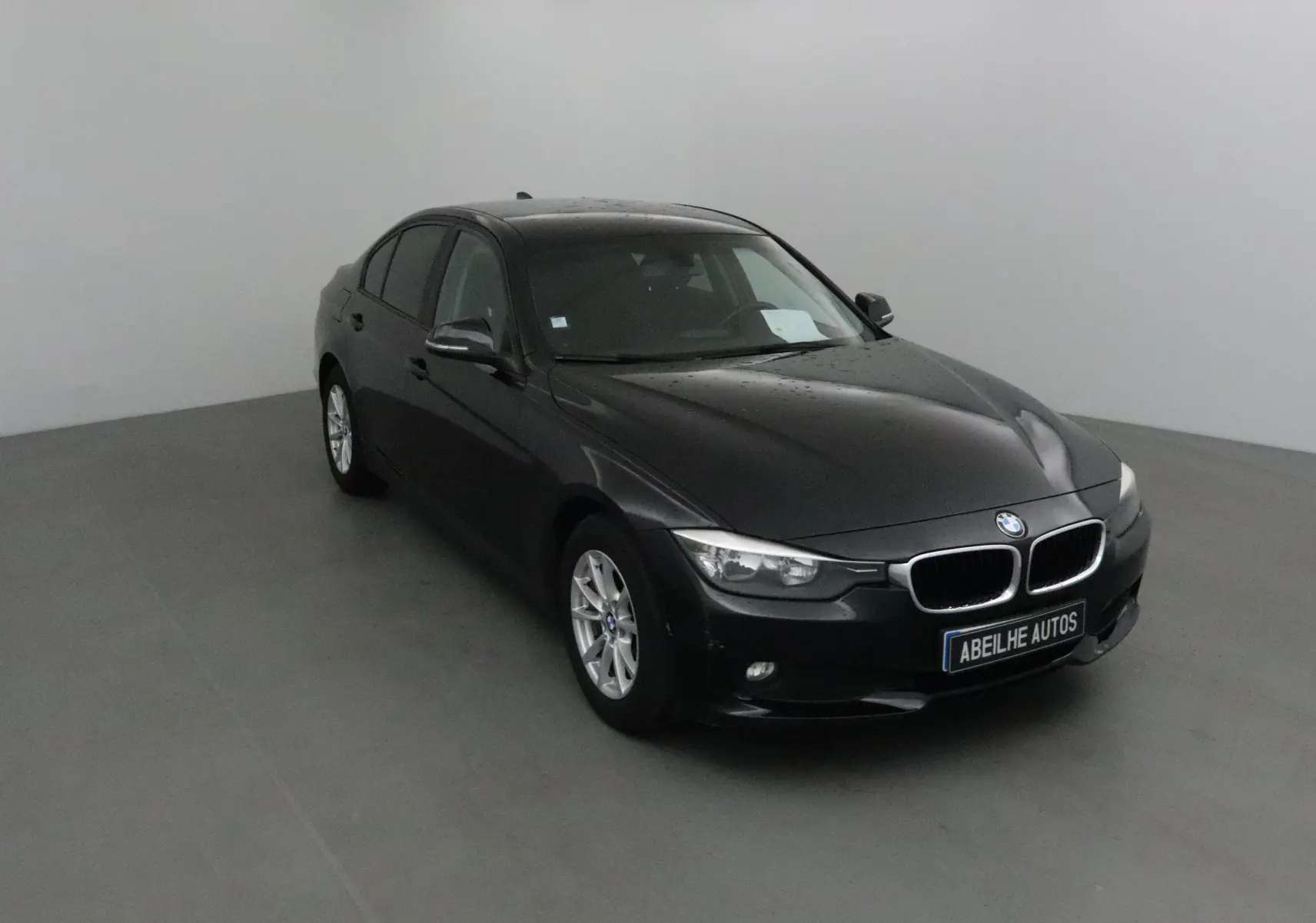 BMW Série 3 316D noire vue en 3/4 avant droit, avec jantes alliage et calandre caractéristique BMW.