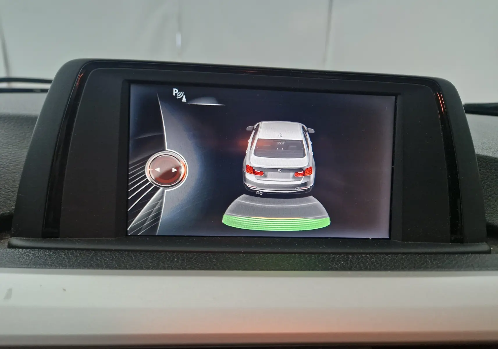 Affichage du système de stationnement assisté montrant une BMW Série 3 noire vue de dessus sur l'écran central.