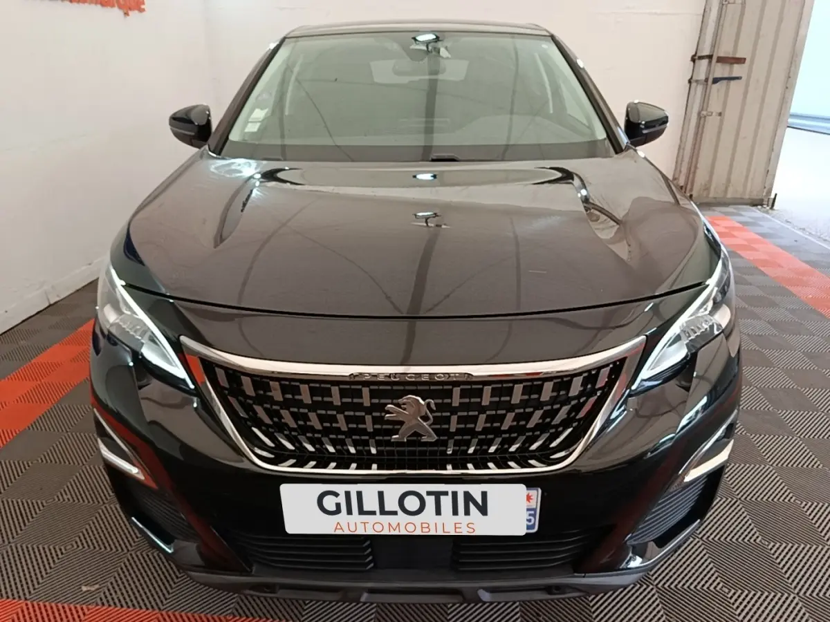 Vue avant d’un Peugeot 3008 noir avec calandre chromée et phares LED, stationné en intérieur sur sol damier.