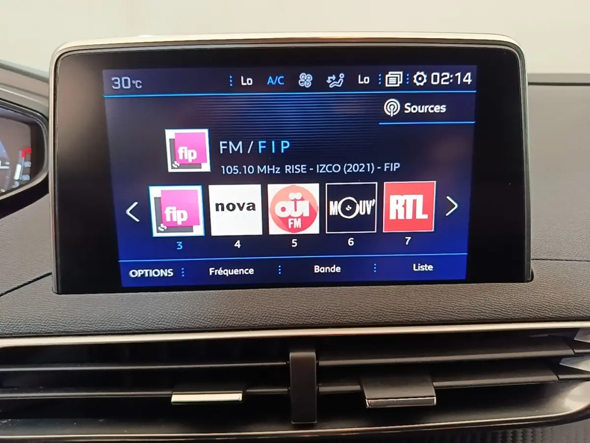 Écran tactile central du tableau de bord du Peugeot 3008 noir, affichant les stations radio FM en mode nuit.