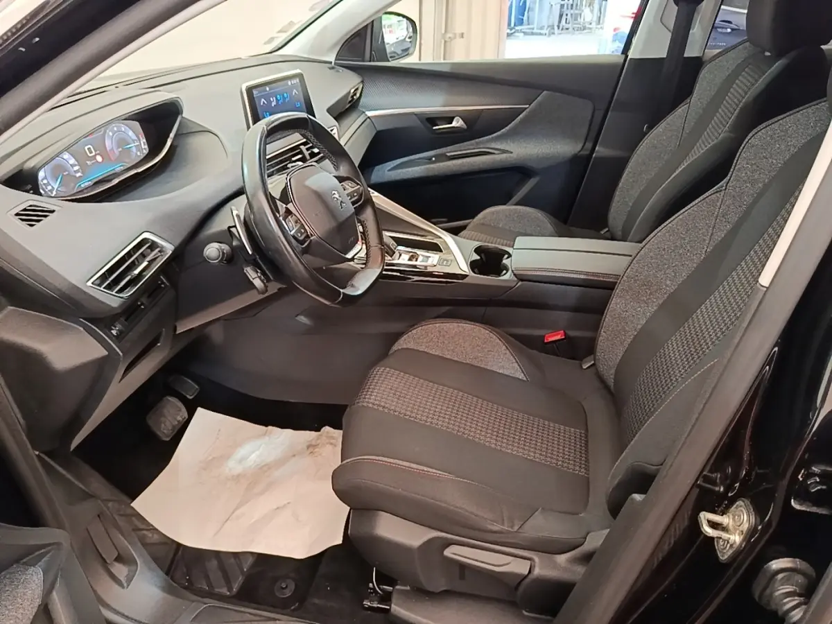 Vue intérieure côté conducteur du Peugeot 3008 noir, mettant en valeur le volant cuir multifonctions et l'écran tactile central.