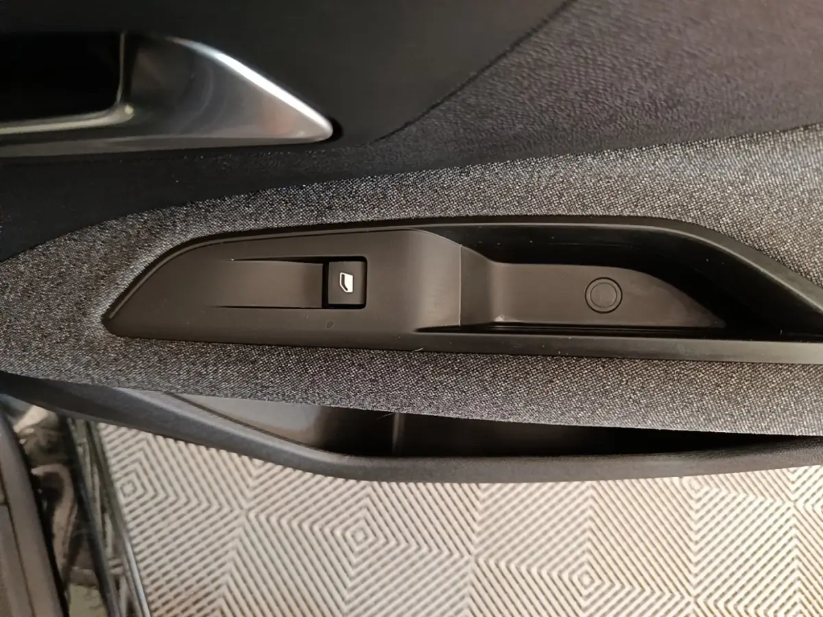 Détail de la commande de lève-vitre sur la porte côté conducteur d’un Peugeot 3008 noir, intérieur tissu gris.