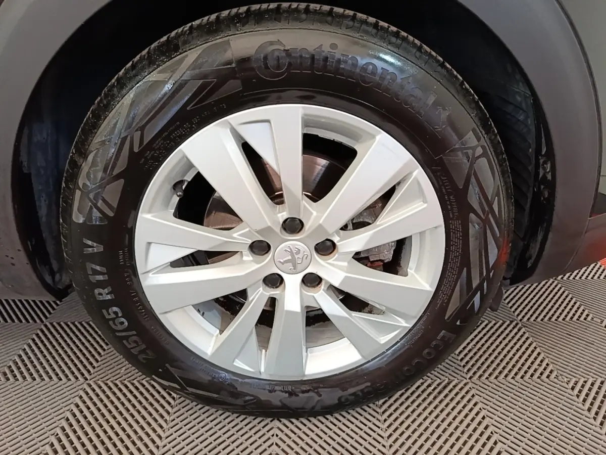 Gros plan sur la roue avant droite avec jante argentée du Peugeot 3008 noir, montrant le logo lion central.