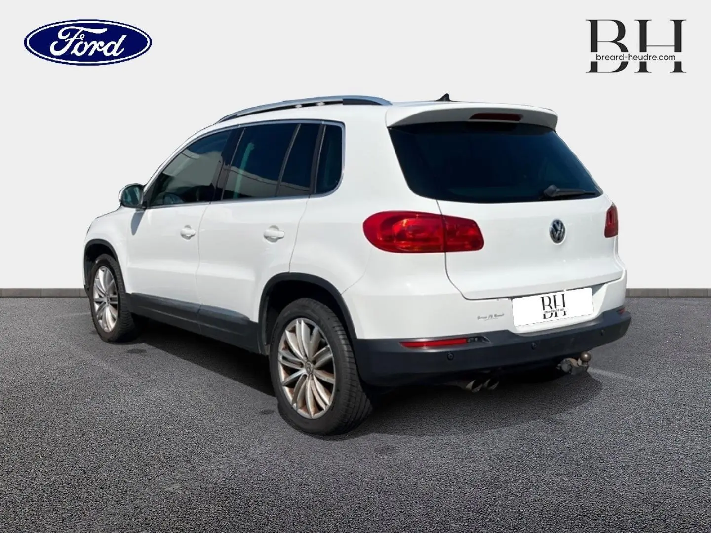 Volkswagen Tiguan blanc Candy vu en 3/4 arrière droit avec barres de toit et jantes alu 17 pouces.