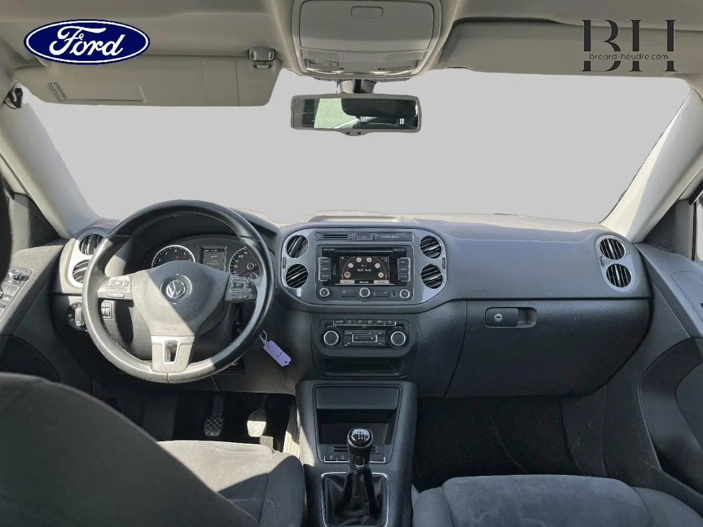 Vue intérieure avant du tableau de bord et volant noir d'un Volkswagen Tiguan 2013, avec écran central et commandes visibles.