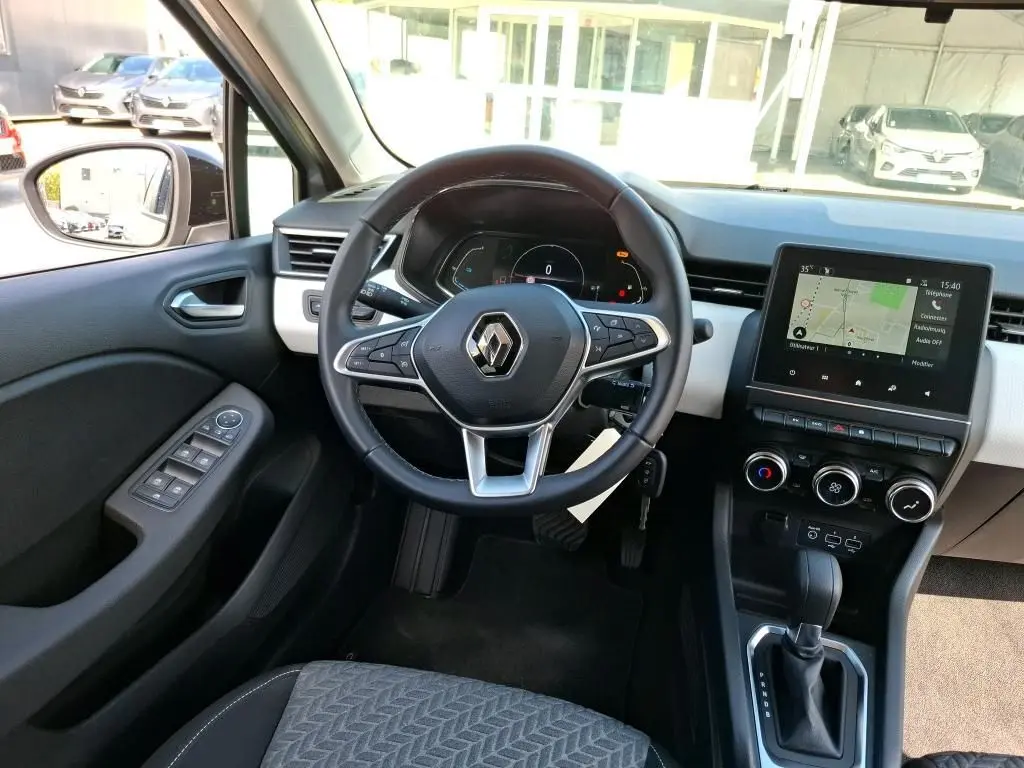 Vue intérieure avant du tableau de bord et volant noir d’une Renault Clio 1.6 E-Tech gris platine avec écran tactile et commandes digitales.