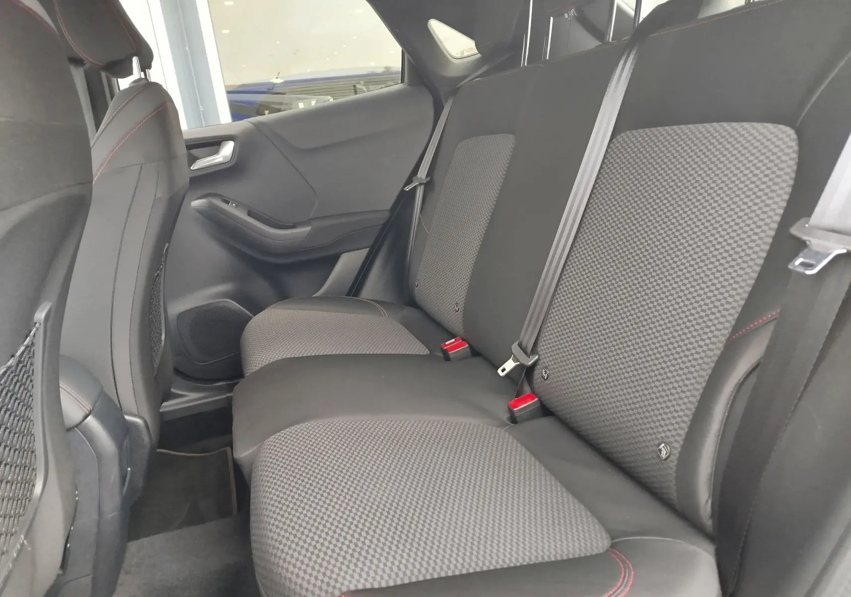 Vue latérale intérieure des sièges arrière en tissu gris à motifs et coutures rouges du Ford Puma 1.0 EcoBoost 2021.