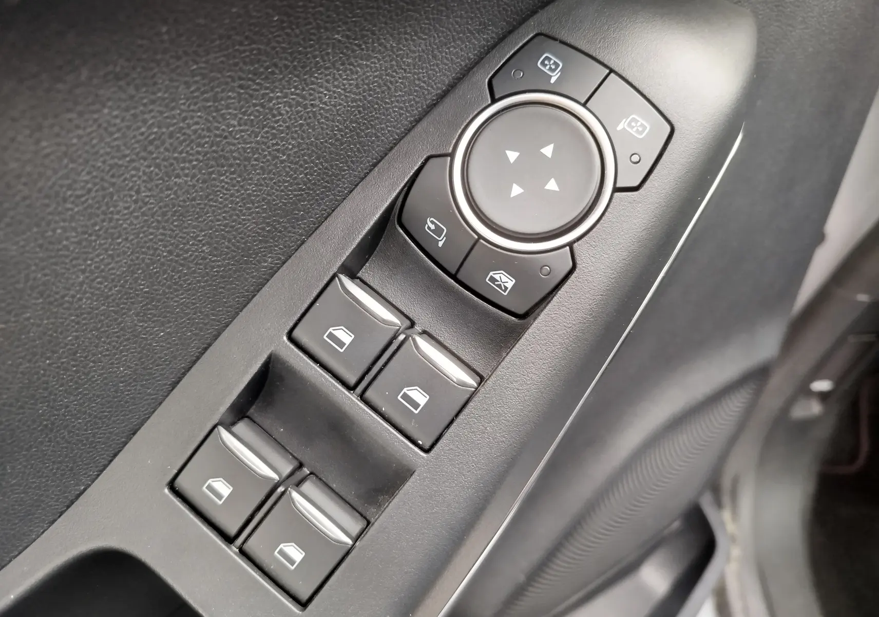 Gros plan sur les commandes de lève-vitres et réglage des rétroviseurs côté conducteur d'un Ford Puma gris 2021.