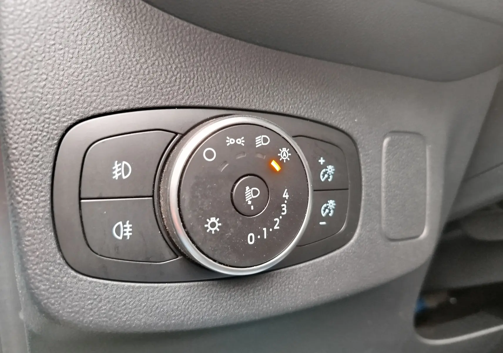 Gros plan sur le bouton de réglage des phares du Ford Puma 1.0 EcoBoost 125ch gris, avec indicateur orange allumé.