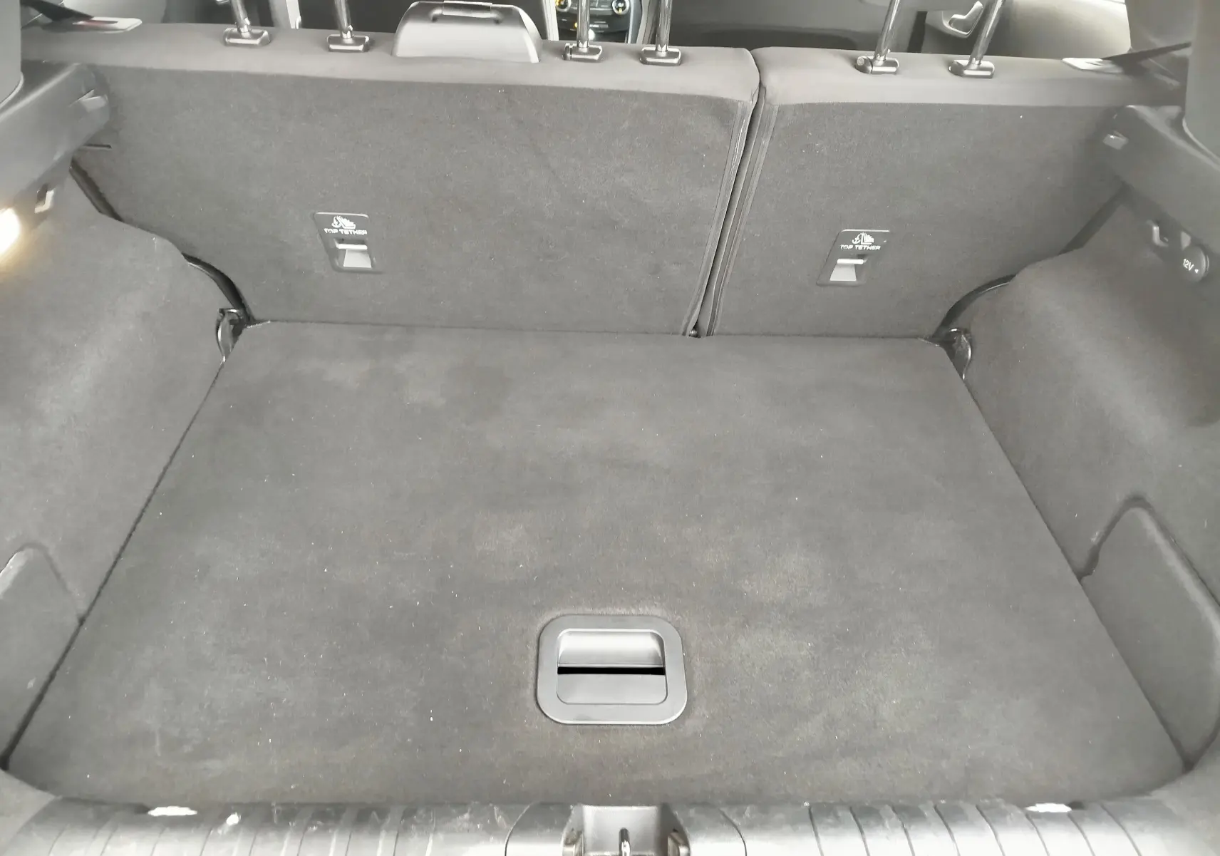 Coffre ouvert vu de l'arrière d'un Ford Puma gris, montrant un espace de chargement propre et bien agencé.