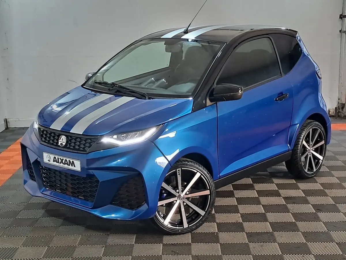 Vue 3/4 avant droite d'une Aixam Ambition bleu avec bandes grises sur le capot et jantes noires à rayures argentées.