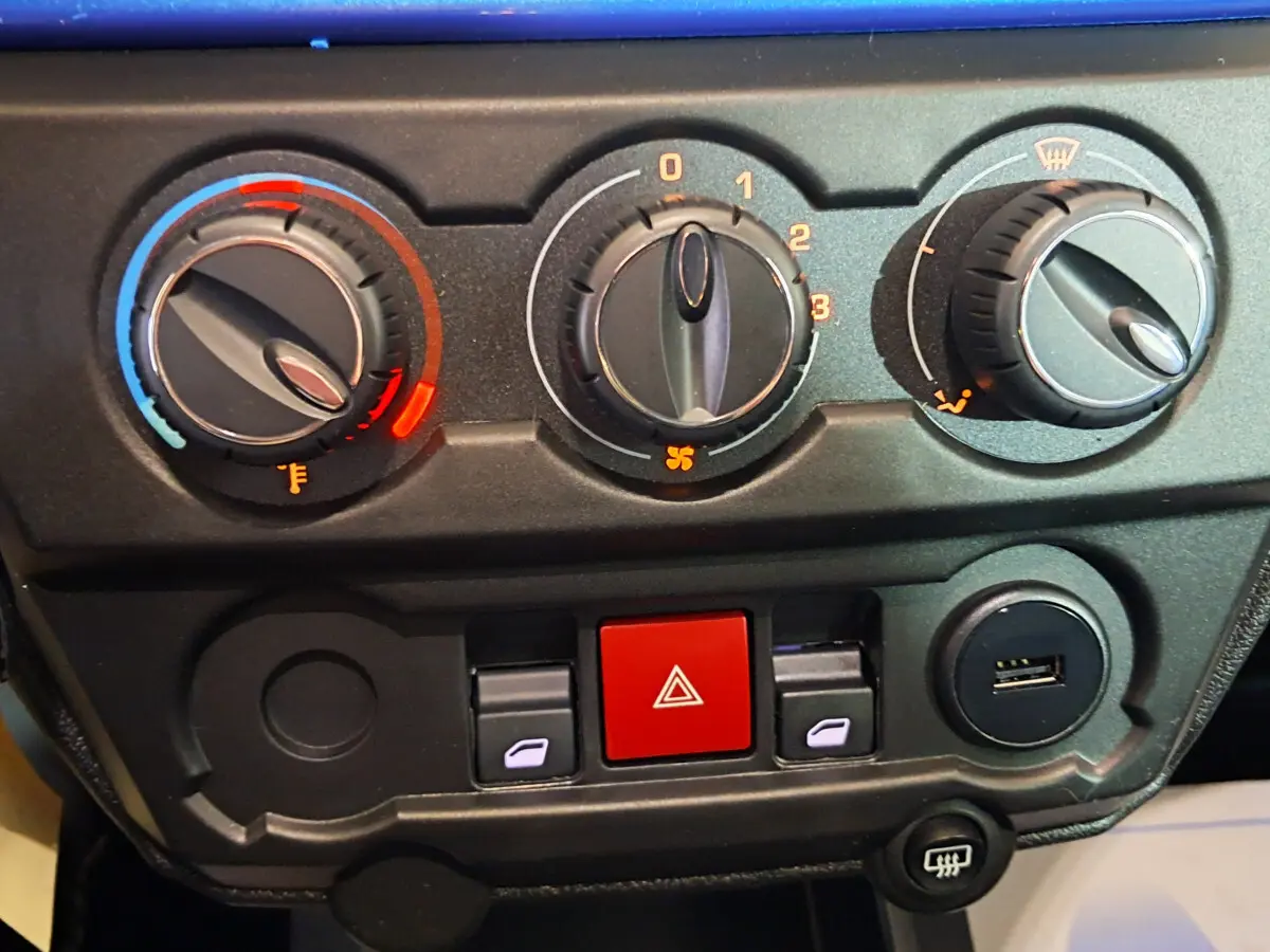 Tableau de bord en gros plan de l'AIXAM AMBITION bleu, montrant les commandes de climatisation et les boutons centraux.