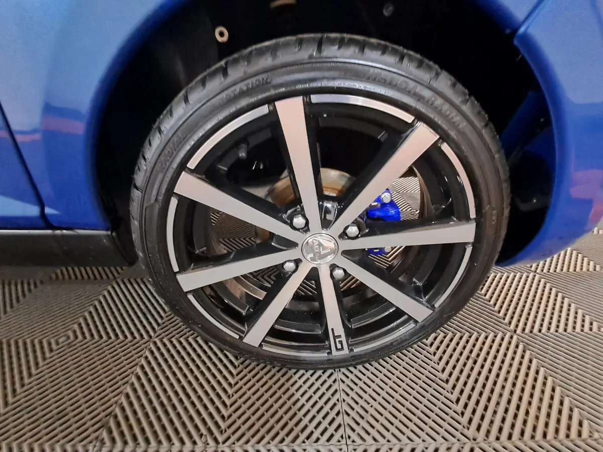 Gros plan sur la roue avant droite de l’AIXAM Ambition bleu avec jante noire et argentée au design moderne.