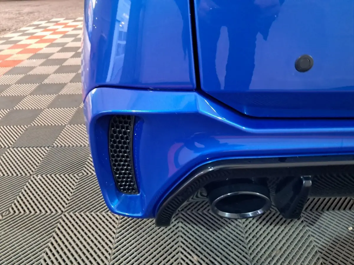 Gros plan sur le coin arrière droit bleu d'une Aixam Ambition 2026, avec sortie d'échappement et prise d'air noire.