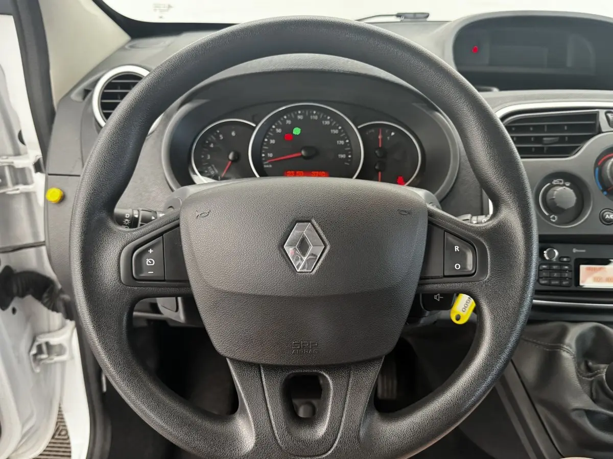 Vue rapprochée du volant noir multifonctions d’un Renault Kangoo blanc, tableau de bord et levier de vitesse visibles.