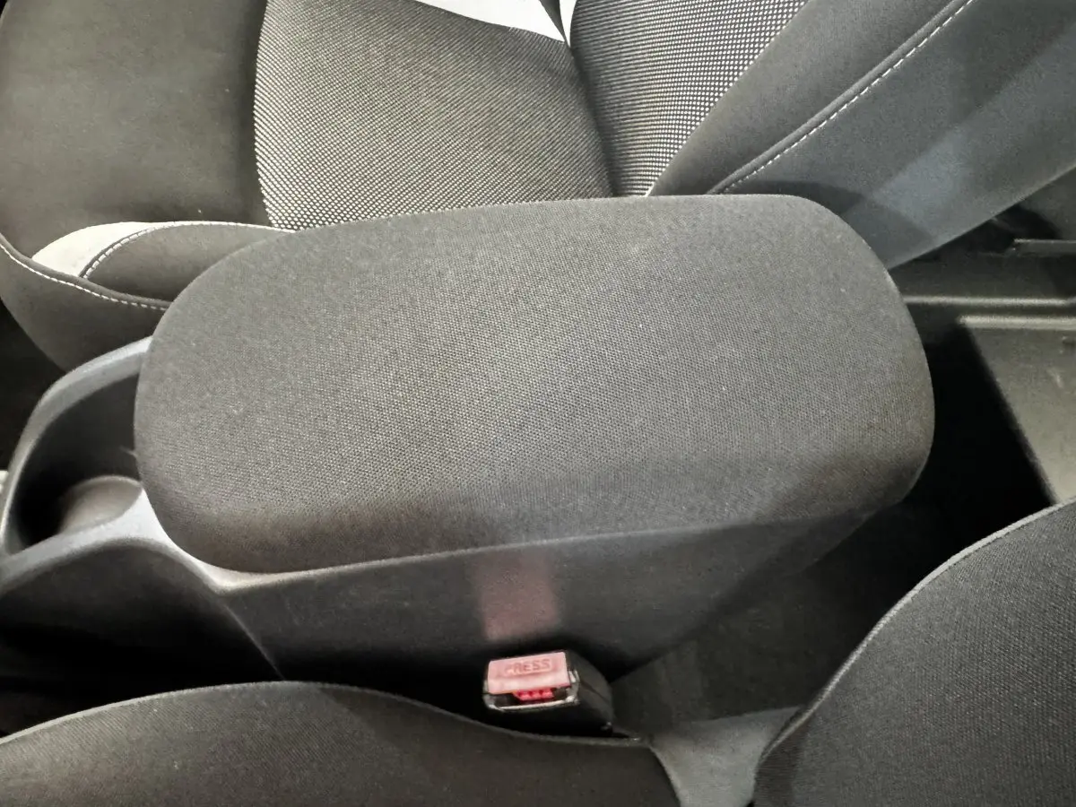 Gros plan intérieur sur l'accoudoir central noir entre les sièges avant du Renault Kangoo Zen blanc de 2016.