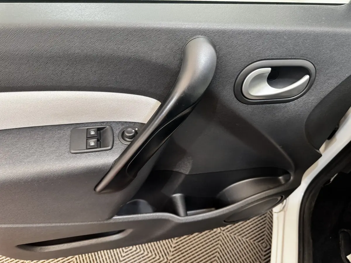 Vue rapprochée de la porte avant gauche blanche du Renault Kangoo Zen 2016, avec commandes de vitres et poignée noire.